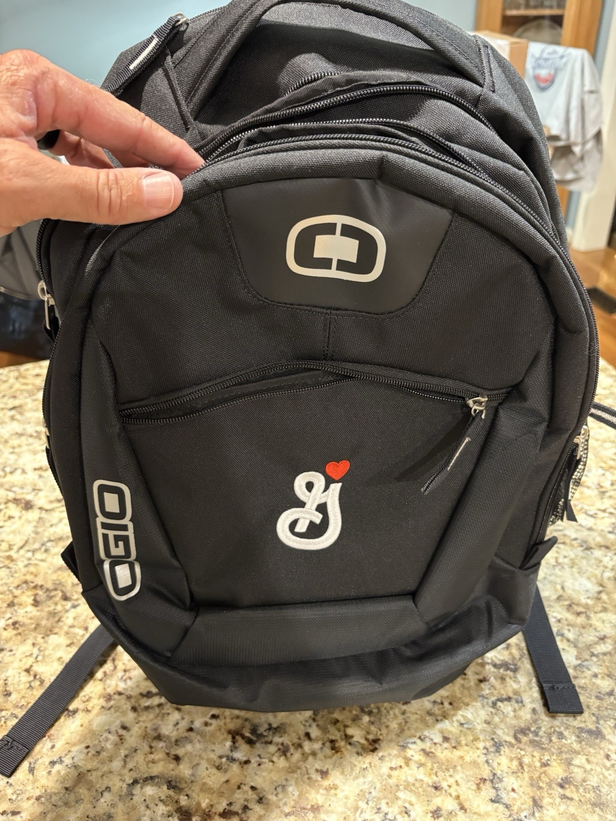 black OGIO Rogue Pack features a custom embroidered logo on the front pocket.